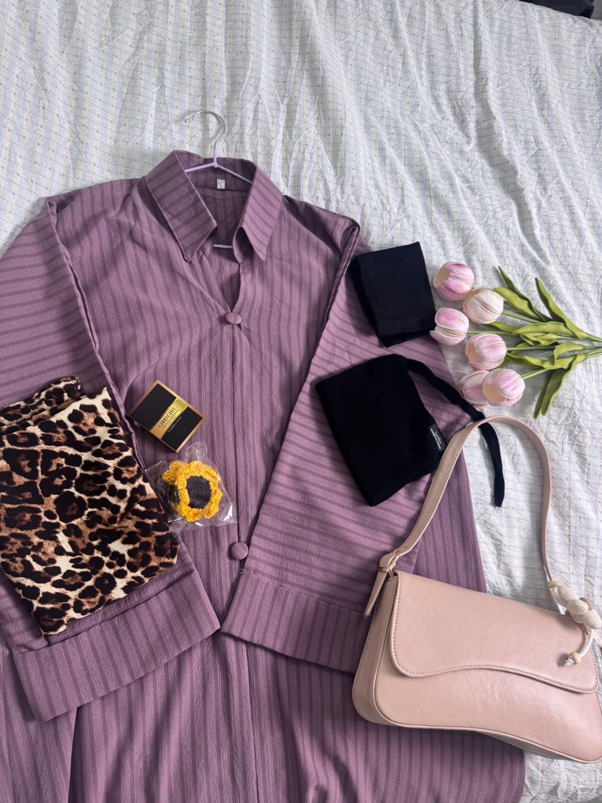 An abaya styled with a leopard hijab, bag, niqab, perfume and sunflower clip