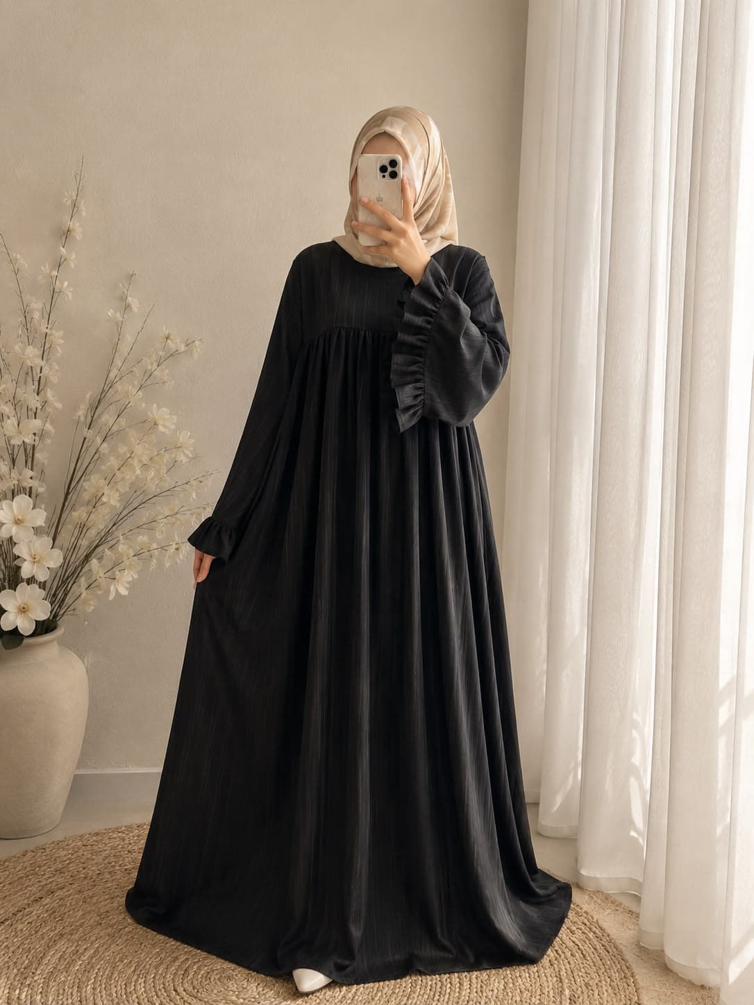 Full-length black abaya with ruffled sleeve cuffs, worn with a light patterned hijab